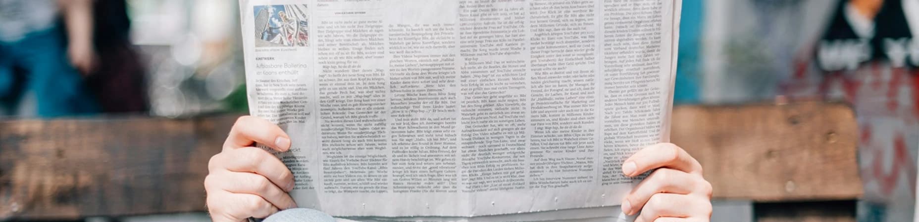 Człowiek czytający gazetę siedząc na ławce