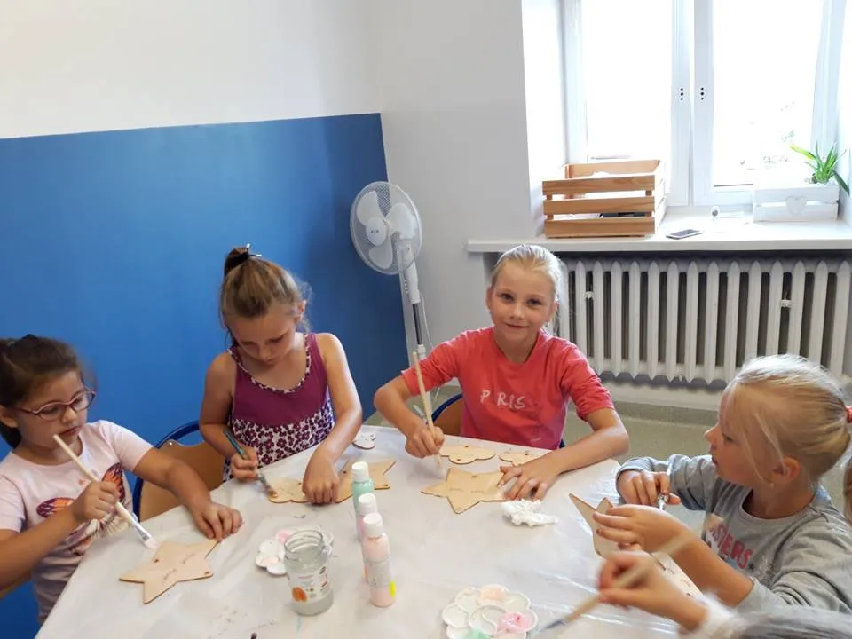 Obraz przedstawia wychowanków SPWD podczas warsztatów artystycznych. Na zdjęciu możemy ujrzeć proces powstawania drewnianych dekoracji.