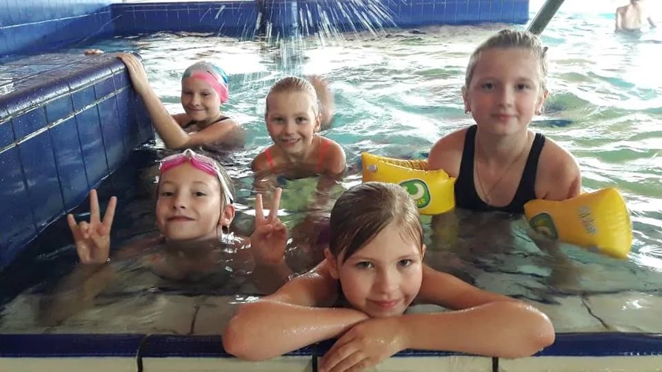 Obraz przedstawia wychowanków SPWD podczas nauki pływania. Na zdjęciu możemy ujrzeć dzieci w basenie.