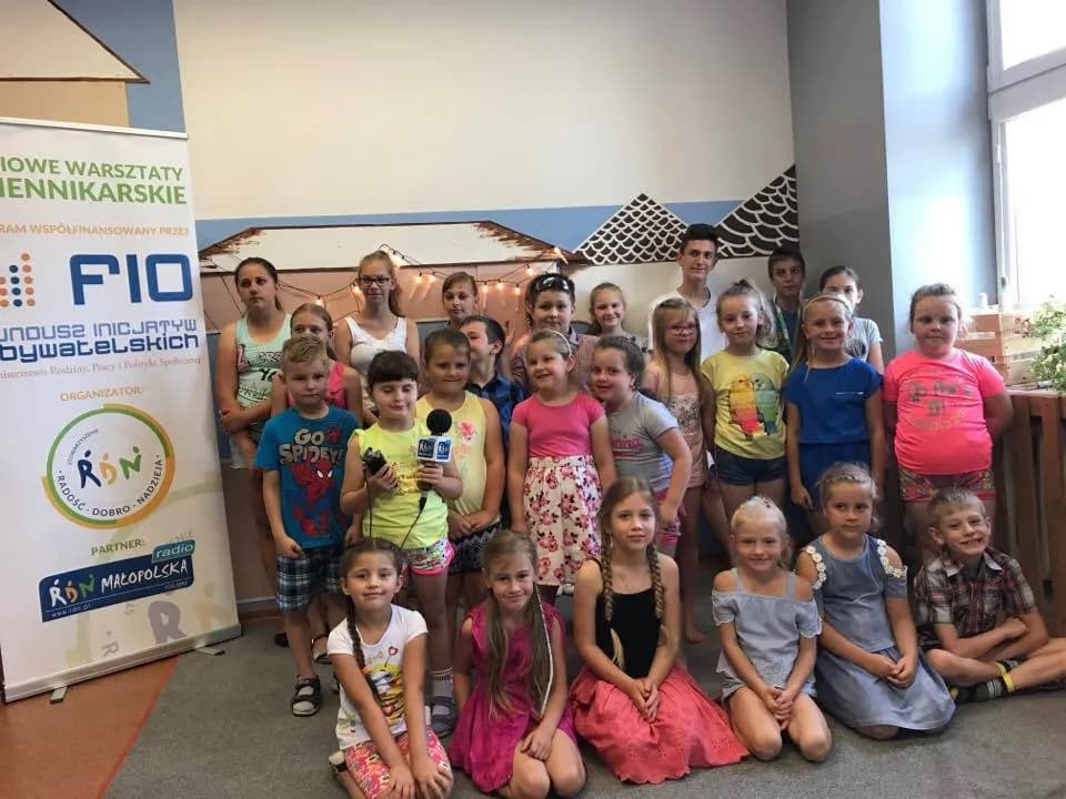 Zdjęcie przedstawia dzieci z placówki pozujące do pamiątkowego zdjęcia z okazji warsztatów dziennikarskich.