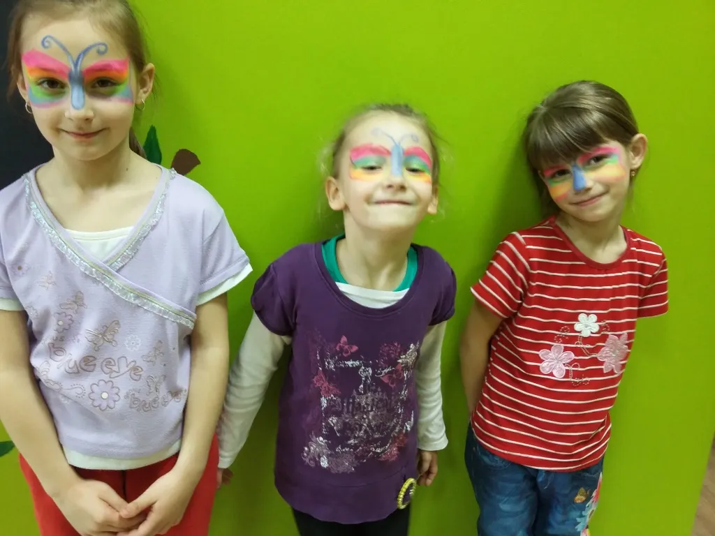 Zdjęcie przedstawia dzieci z pomalowanymi twarzami cieszące się wiosną.