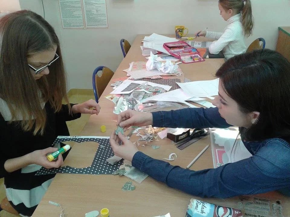 Zdjęcie przedstawia dwójkę podopiecznych oraz osobę prowadzącą zajęcia razem tworzących upominki z okazji Dnia Babci i Dziadka.