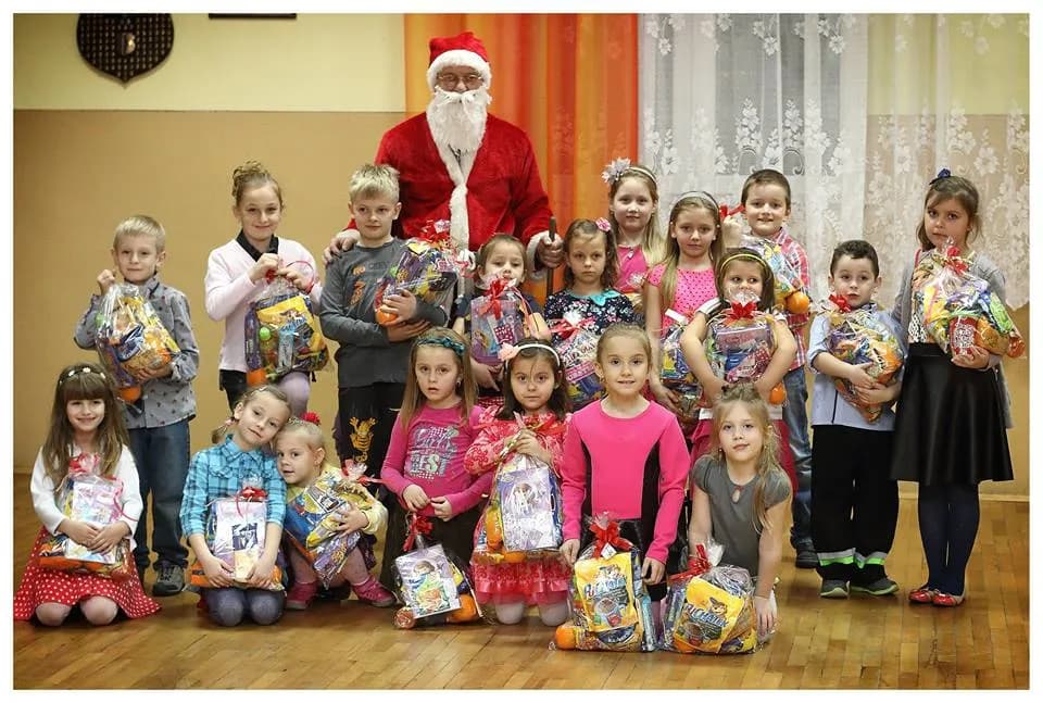 Zdjęcie przedstawia dzieci z placówki ustawione do zdjęcia z świętym Mikołajem oraz prezentami od Niego.