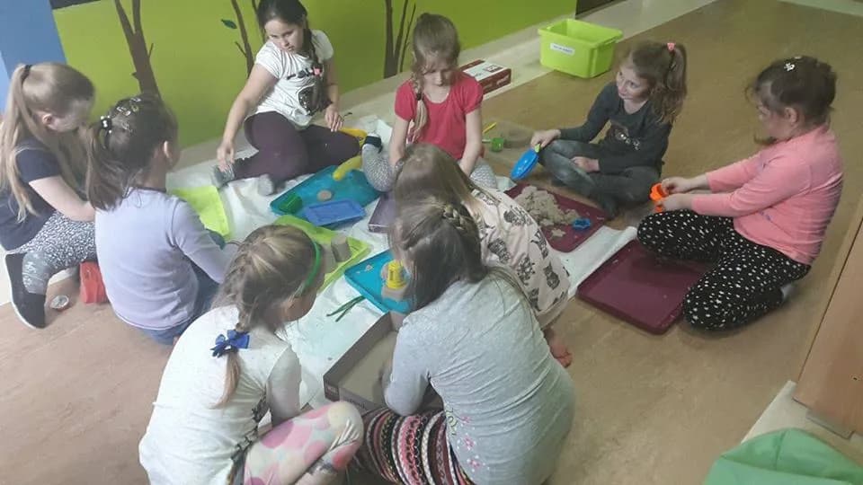 Zdjęcie przedstawia dzieci bawiące się w "domowej piaskownicy" na podłodze w pokoju placówki SPWD.