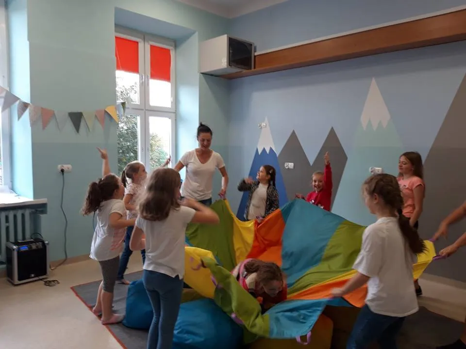 Obraz przedstawia zajęcia socjoterapeutyczne. Na zdjęciu możemy ujrzeć wychowanków podczas różnego rodzaju zabaw związanych z socjoterapią.